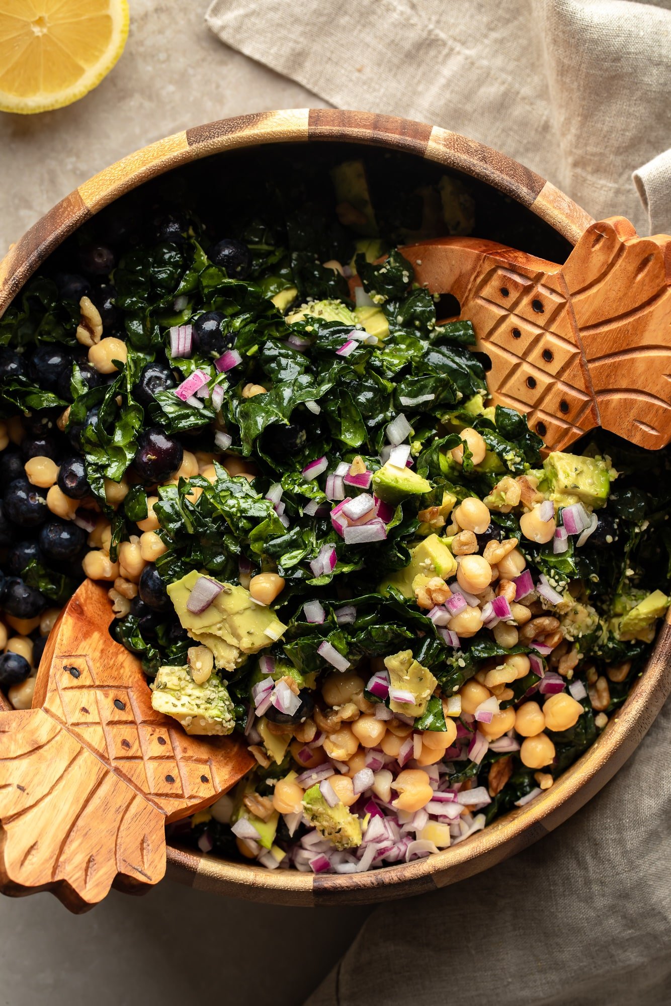 Using 2 tweezers to throw a Kale salad together in a large bowl.