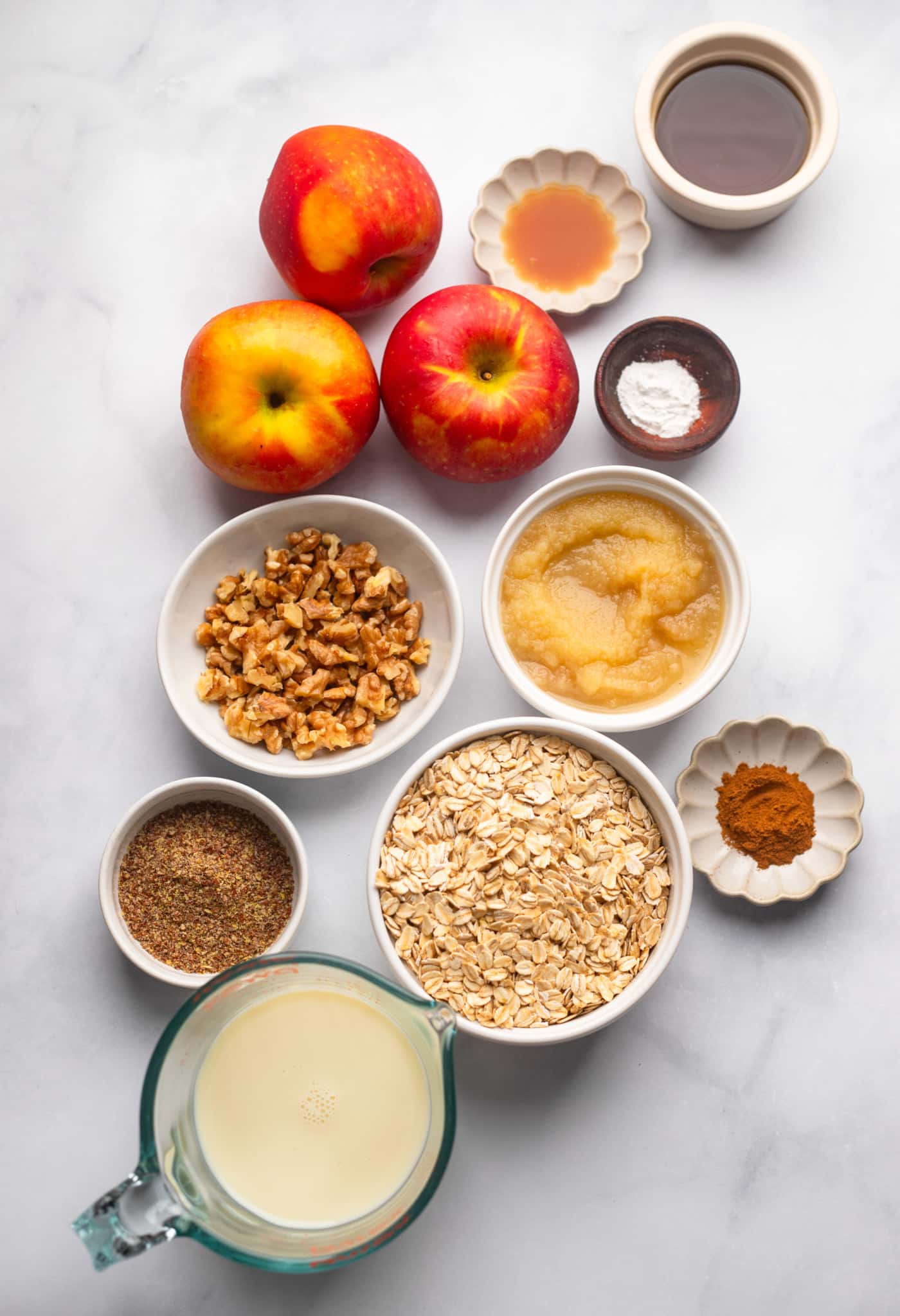 Ingredients for oats in the apple oven in individual white bowls.