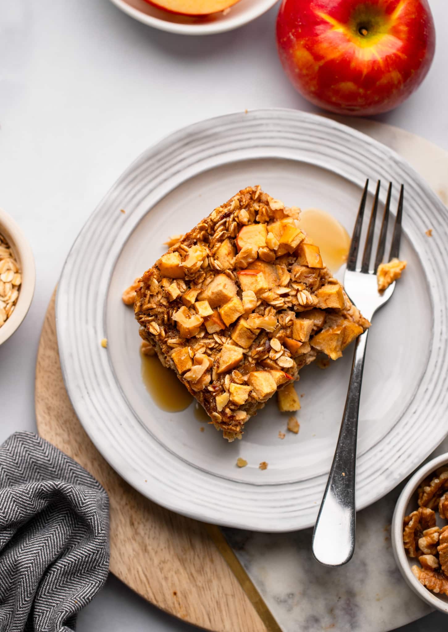 A slice of oatmeal in the apple oven on a white dish with a fork next to it.