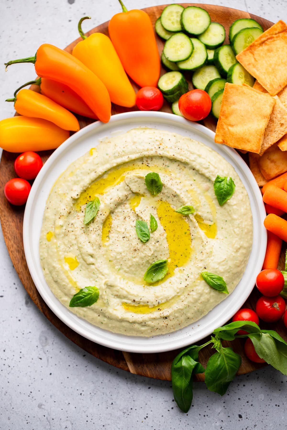 The white bean immerses in a white bowl surrounded by vegetables and cookies.