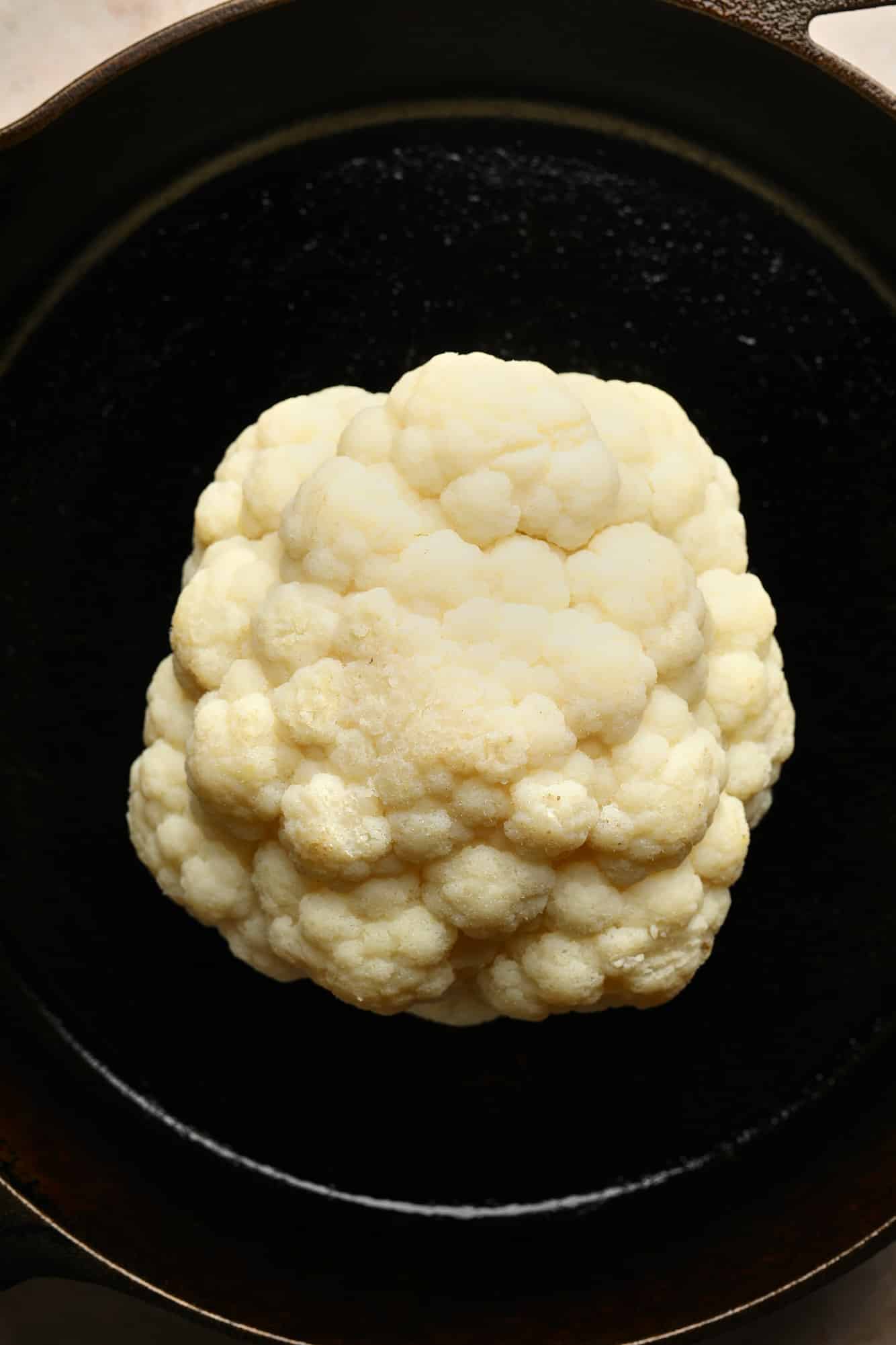 A cauliflower head in a black pan.