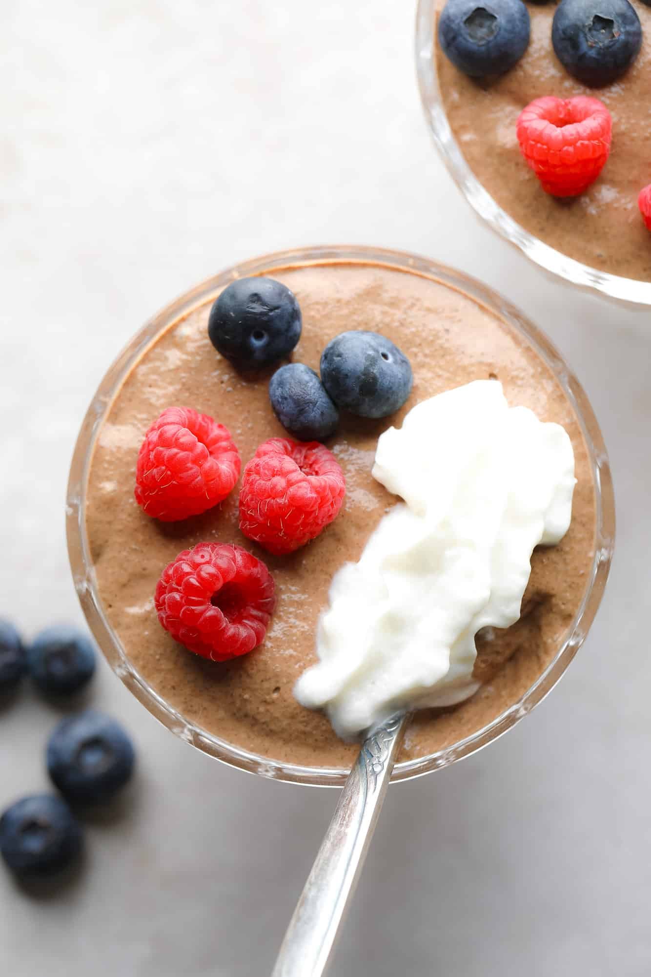 Near a jar of chocolate chia pudding topped with berries and whipped cream.