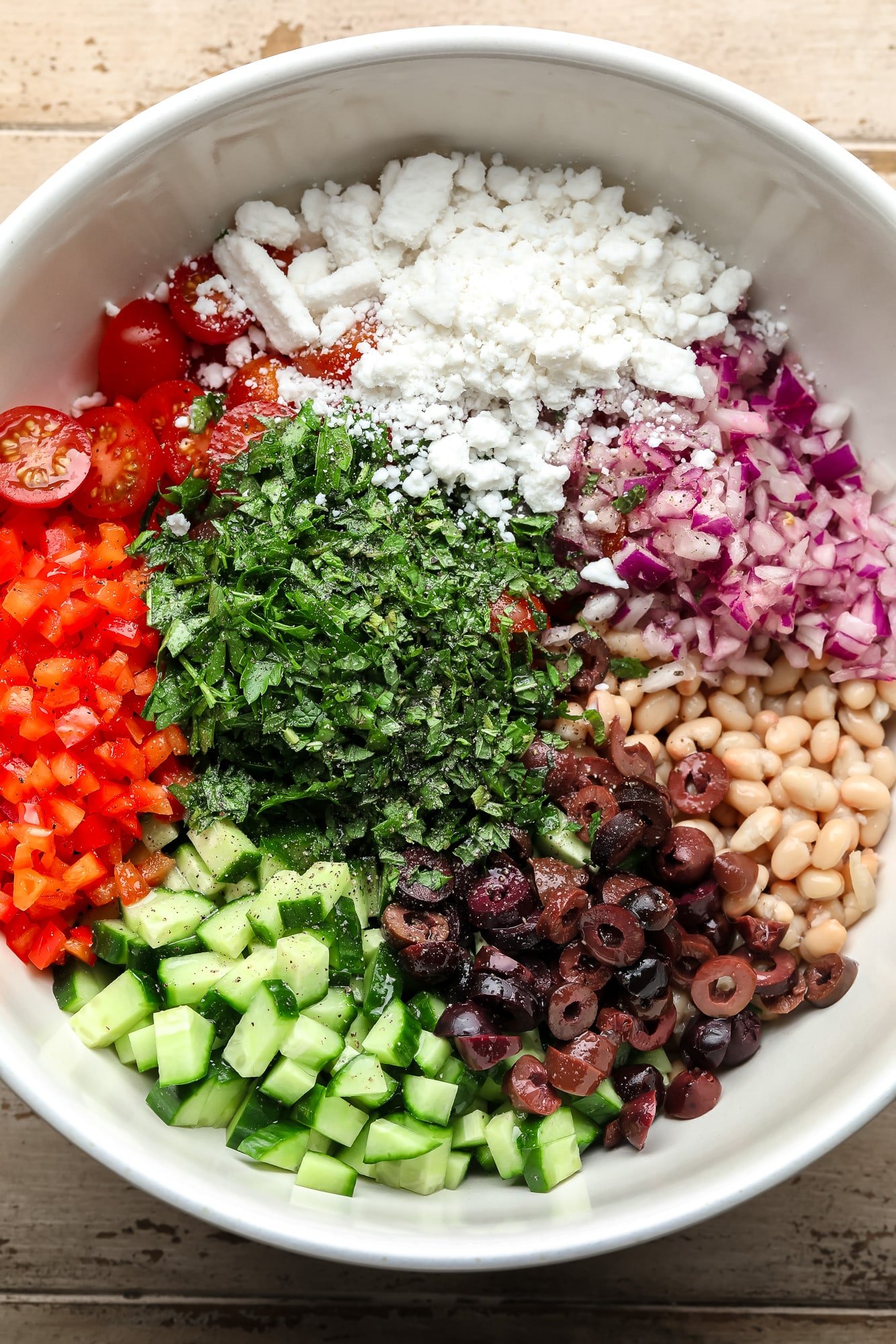 The ingredients for white beans salad in a large white bowl.