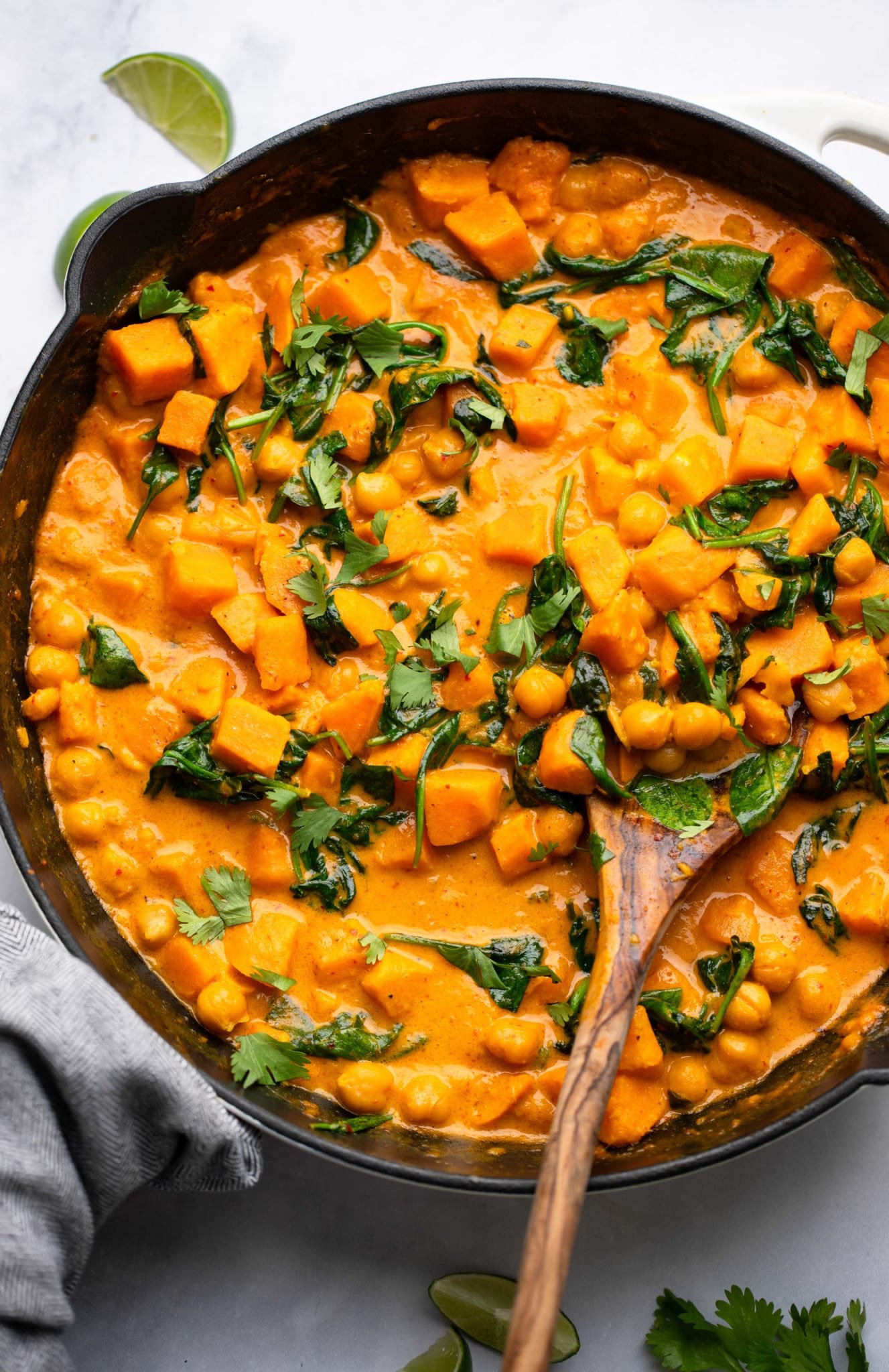Use a wooden spoon to take the sweet potato curry in a black pan.