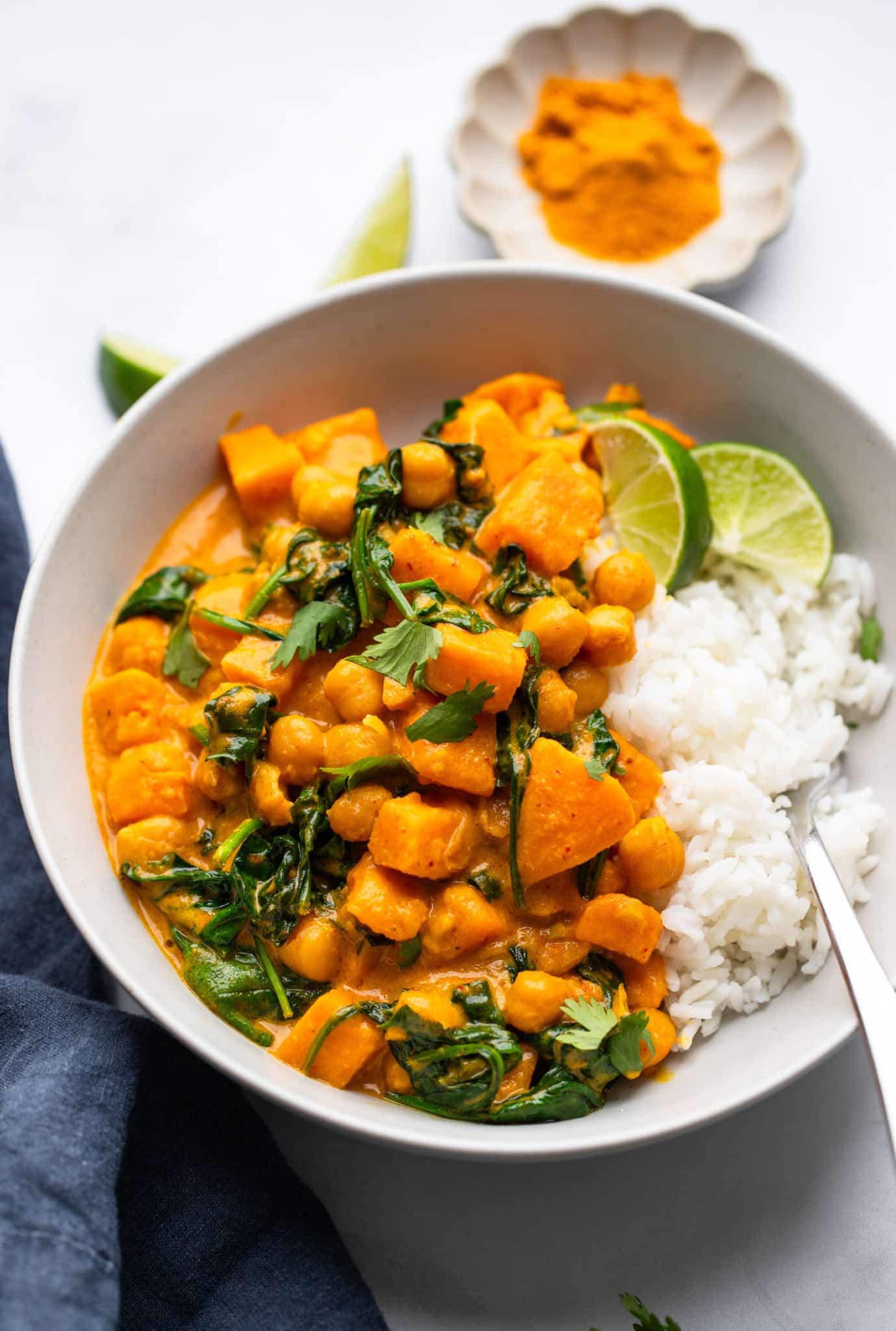 Sweet potato curry with chickpeas served with white rice in a white bowl.
