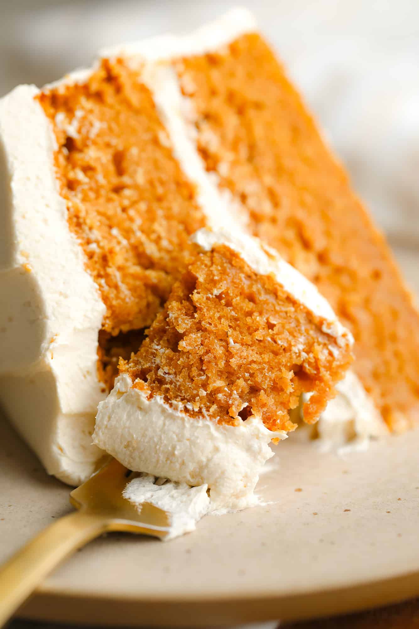 Near a fork that holds a bite of pumpkin species cake.