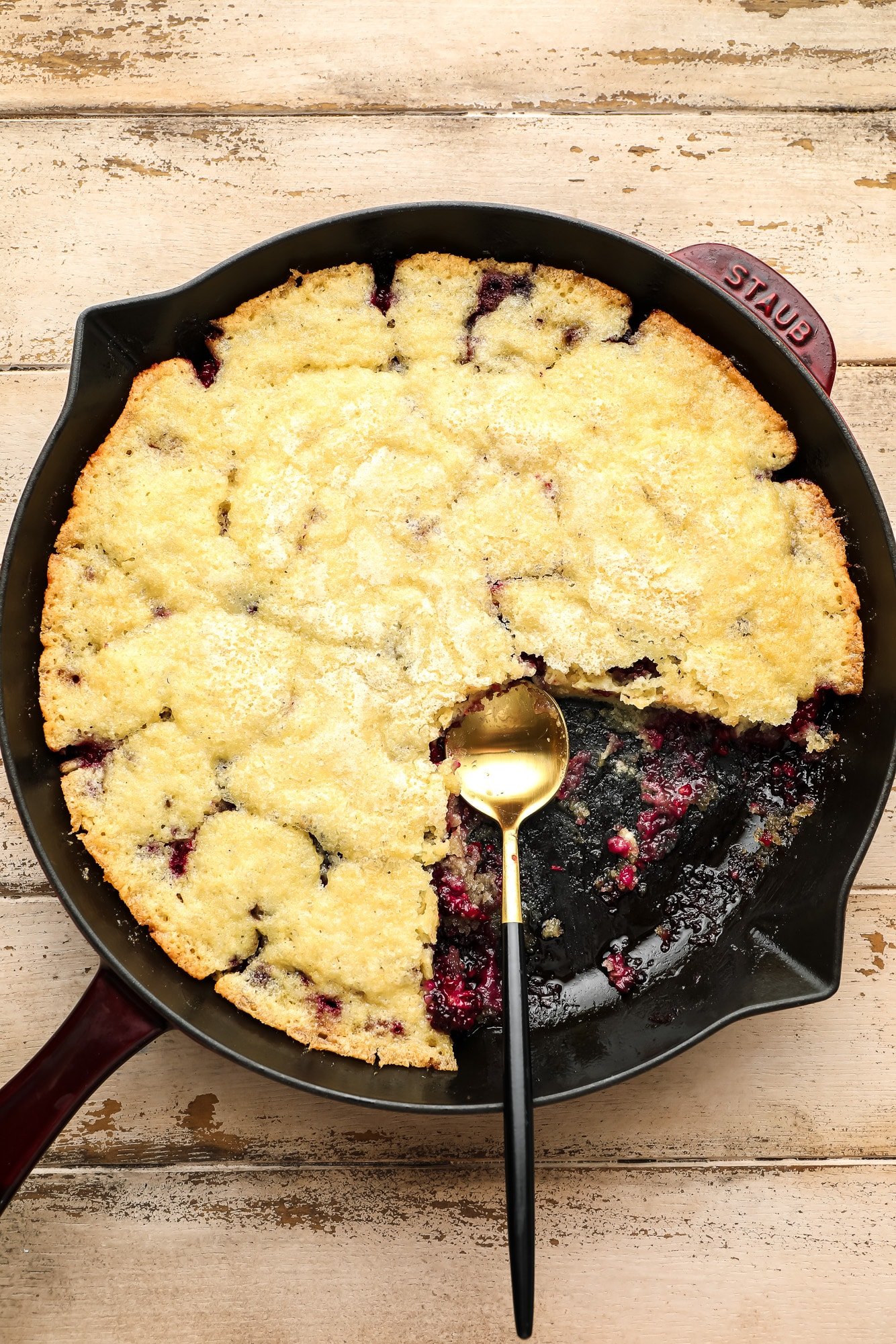Using a spoon to serve a baked blackberry pants from a black paella.