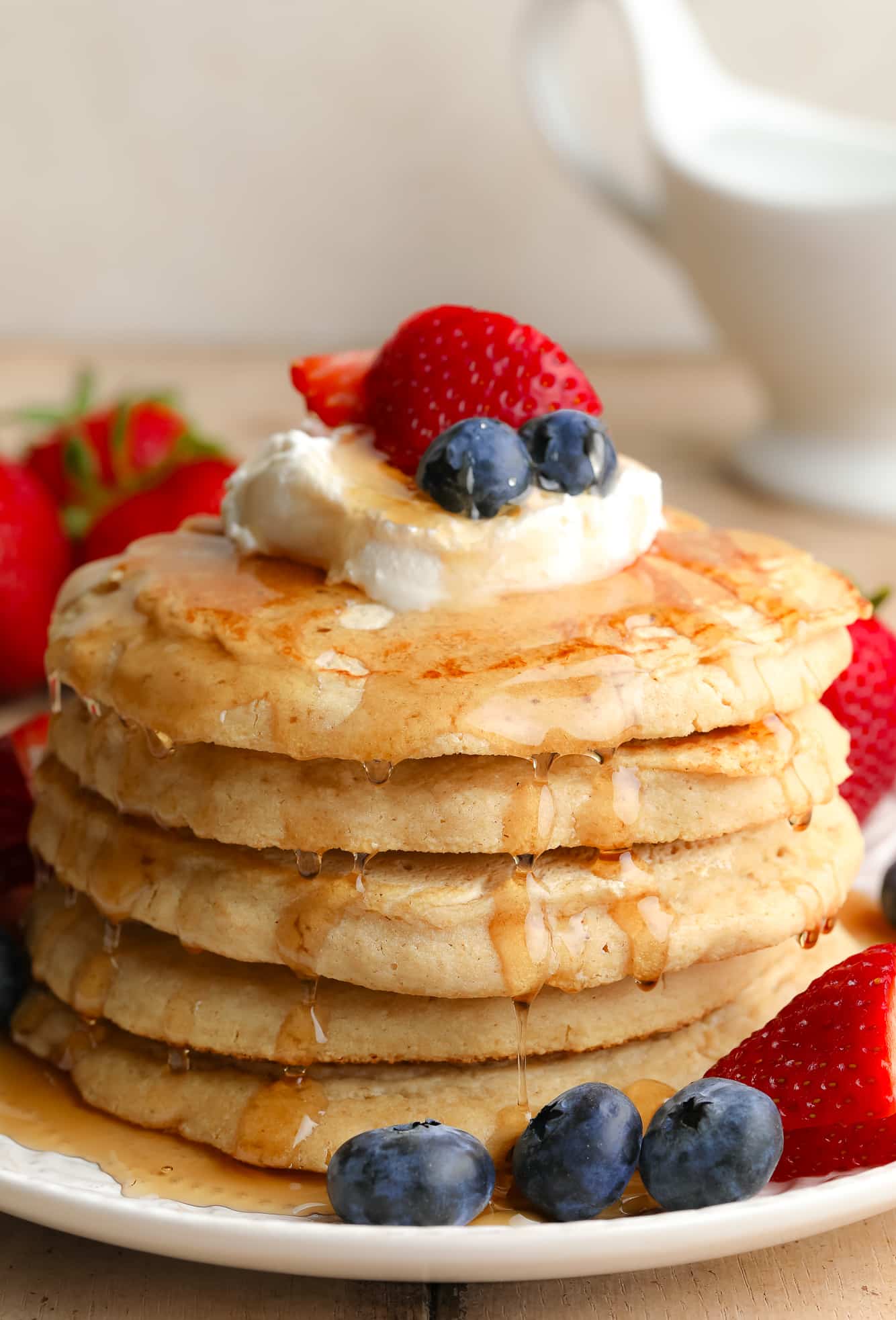 A pile of vegan oatmeal pancakes with butter and berries on top.