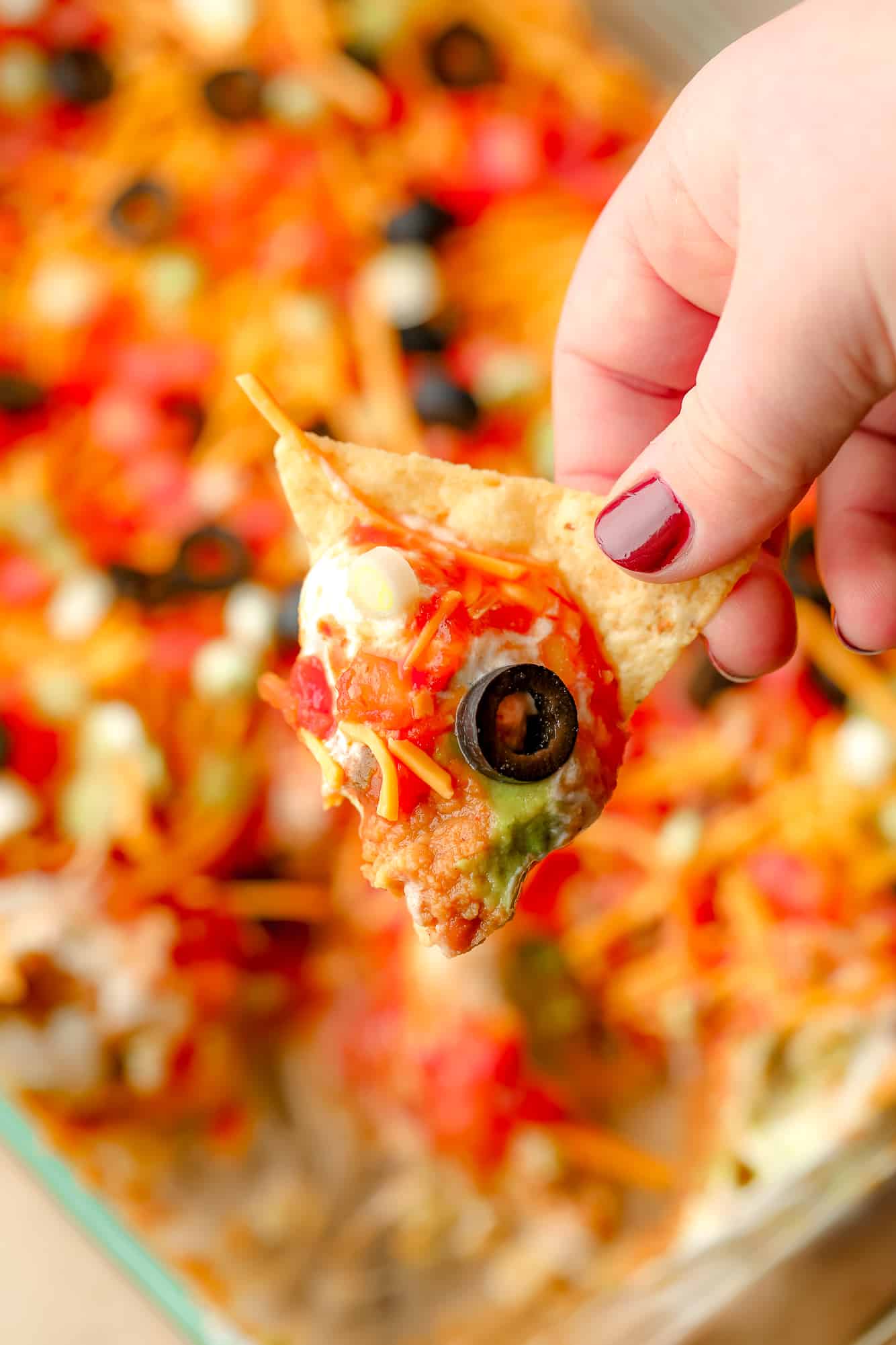 Womans's hand holds a trout chip that has been sunk in the vegan bathtub.