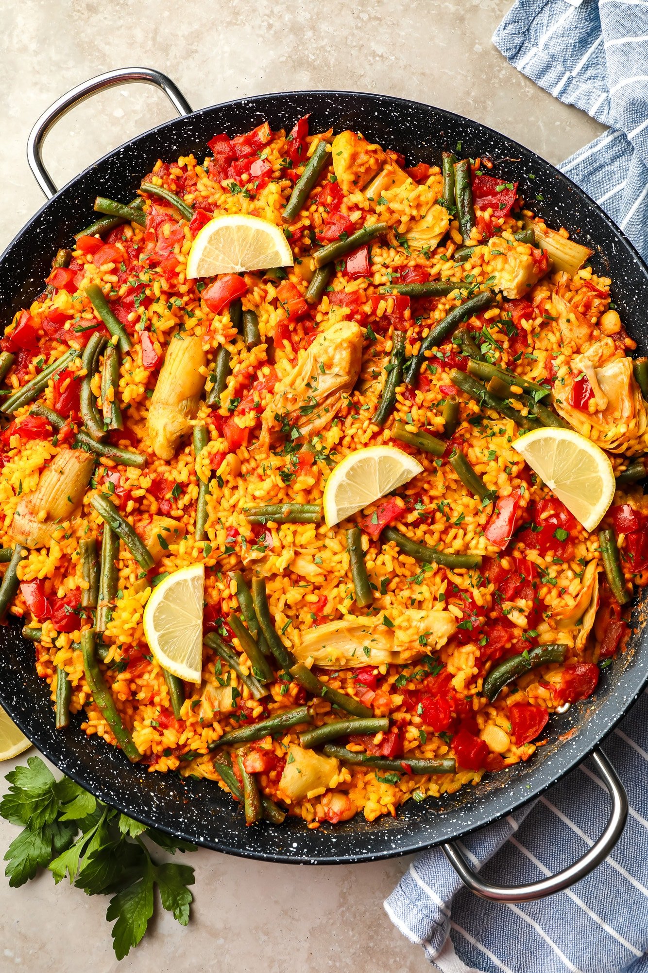 Vegan pan topped with lemon slices in a large pan of black paella.