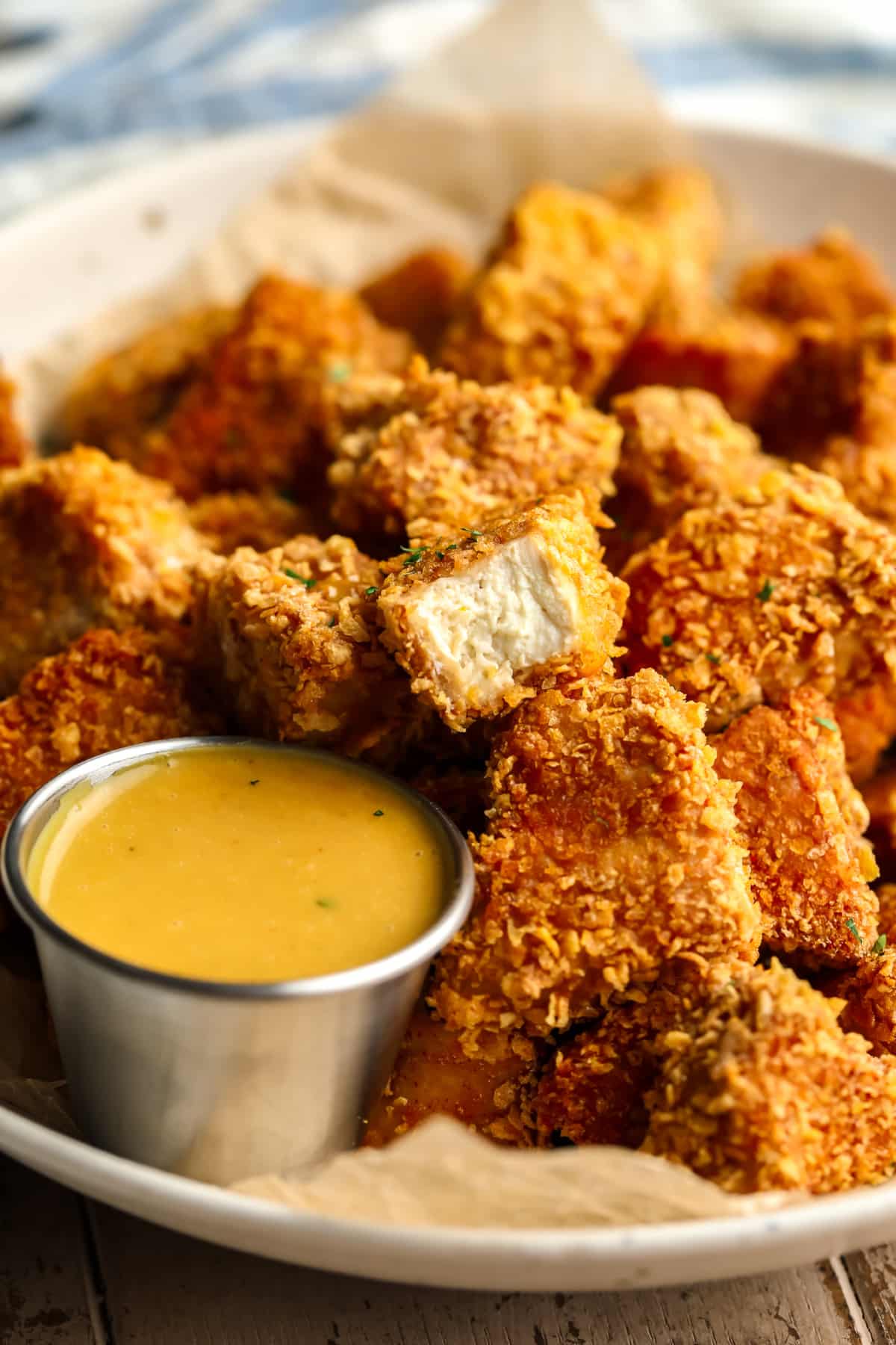 Many vegan chicken pepites in a bowl with one showing its interior