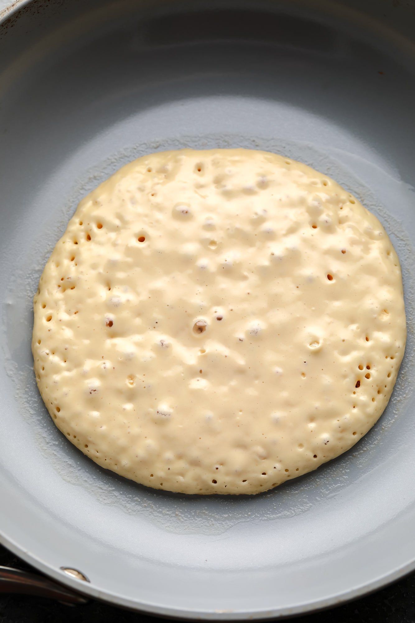 Cook a vegan crepe in a gray pan.