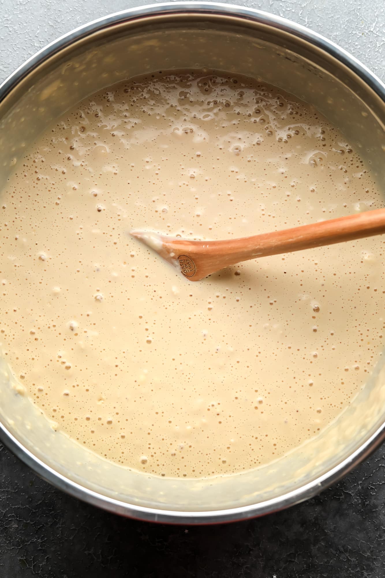 Use a wooden spoon to stir the vegan crepe whip in a large metal bowl.